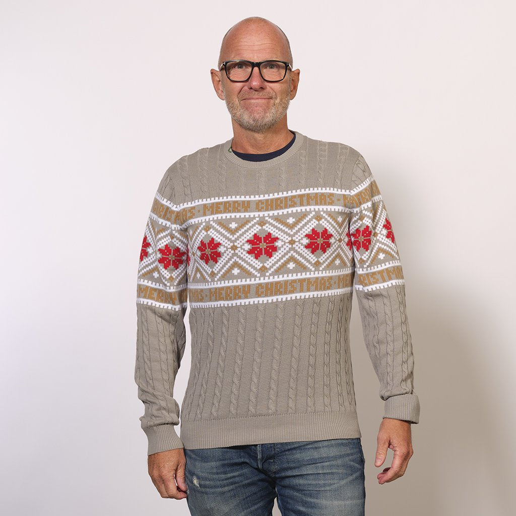 En man i en grå jultröja med snöflingor på.